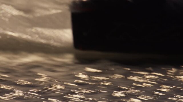 Kitesurfer on twintip do transition move carving through seawater, sunset slowmo