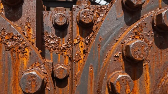 Close-up of heavily rusted industrial machinery with bolts and metal plates, textures and decay
