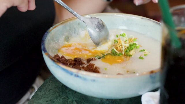Close Up of Person Eating Asian Rice Porridge with Egg Yolk