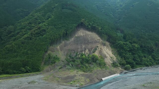 Aerial drone footage of landslide on forested mountain slope along Abe River, Shizuoka