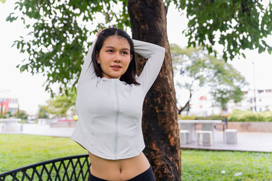 Asian sporty woman stretching before workout in public park