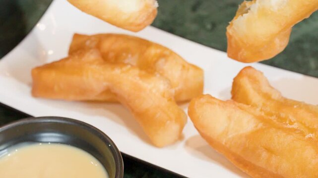 Person Dipping Fried Dough Sticks into Sweet Condensed Milk Sauce