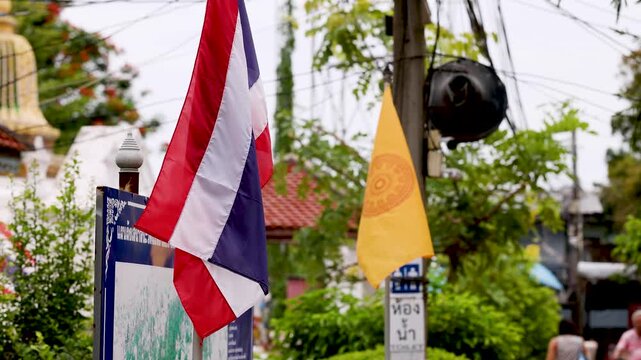 Thai National and Buddhist Flags Waving at Temple Entrance