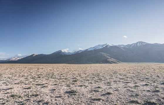 A desert landscape in the highlands of the Pamirs on a sunny summer day with mountains, peaks, and ridges of the Tien Shan mountain range