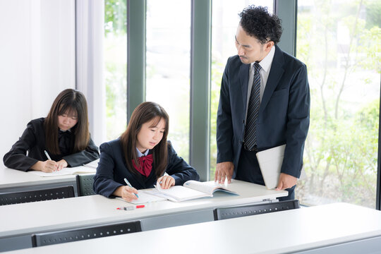 Japanese middle and high school girls studying with teachers providing one-on-one instruction in cram school or school classrooms; scenes from prep school and high school classes