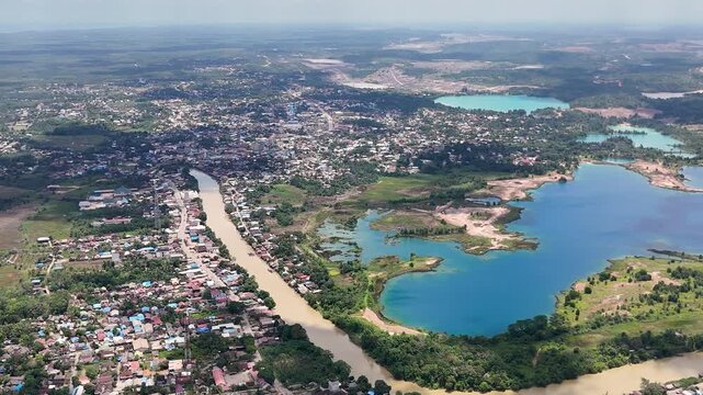 Drone shoot of a coal mining area near a residential area and nearby a blue lake from a former coal mine in South Kalimantan