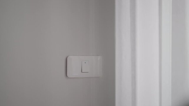 Female finger pushing for turn on light switch on white wall at home room. Woman hand turn off lighting Switch. Energy Saving, energy power control, electrical, eco environment, and lifestyle concept