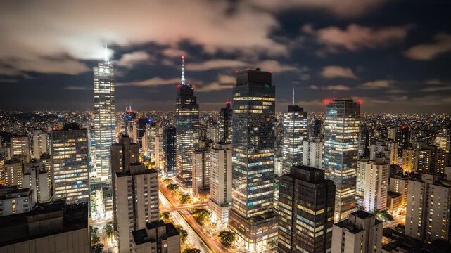 Night city skyline glows above a dense urban grid, alive tonight