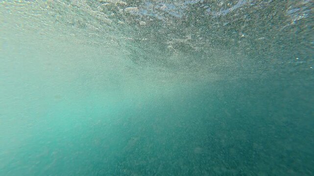 Exciting first-person perspective of jumping off a rusty metal ladder into the turquoise ocean, with the camera submerging underwater and then resurfacing to a view of the sunny coastline