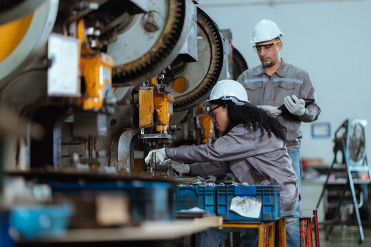 Workers operate machinery in a factory at a manufacturing site during the day