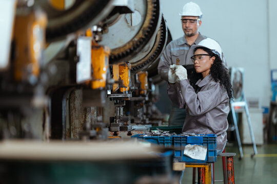 Workers operate machinery in a factory at a manufacturing site during the day