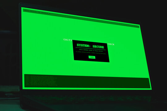 Laptop screen displaying green system secure alert popup window in darkness. Concept of cyber security success, computer protection active, data privacy, and network defense.