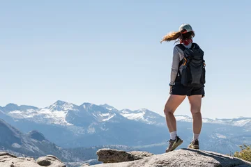 Female hiker standing on a mountain ridge with wind-blown hair © Diana Vyshniakova