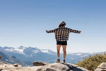 FemalehHiker with arms outstretched wearing a flannel shirt on a mountaintop © Diana Vyshniakova