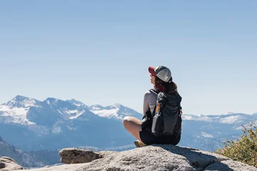 Female hiker sitting cross-legged on a rock in the mountains © Diana Vyshniakova