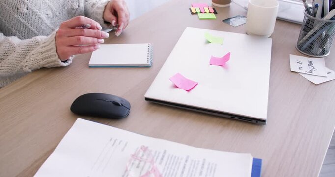 Business failure. Office lifestyle. Unrecognizable woman manager working at desk writing task in notebook with sticky notes on laptop.