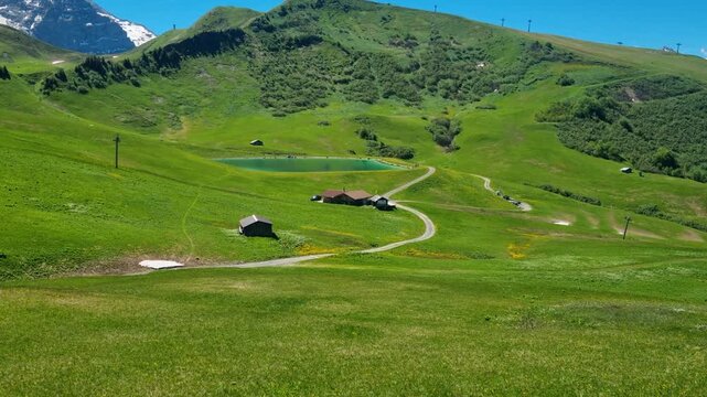 Panoramic view from Hahnenmoos in the Bernese Oberland overlooking vibrant alpine meadows and the Metschstand peak under a clear blue summer sky, showcasing the pristine beauty of the Swiss Alps