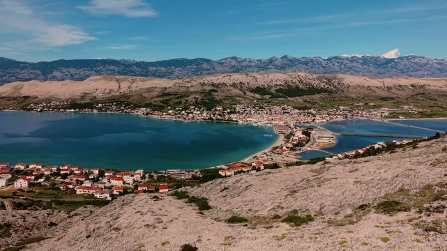 Pag town and salt pans on Pag island with Velebit mountain range in the background, Croatia, aerial view