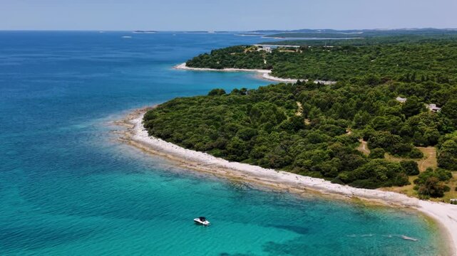 Small yacht boat in a shallow turquoise Adriatic Sea lagoon next to a pine forest near Brijuni, Croatia