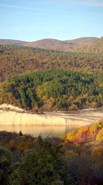 Fall. Autumn foliage creates a breathtaking view over a calm lake surrounded by hills. Vibrant nature concept