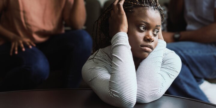 Person sitting with a thoughtful expression, hands on head, indoors.