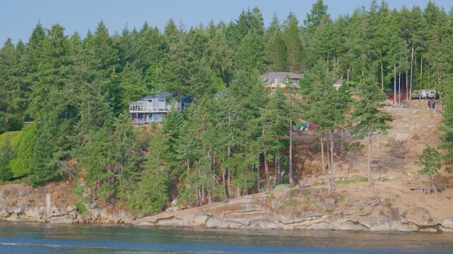 Luxury waterfront homes on rocky cliffside in temperate forest