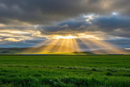 Sunbeams shine through dark clouds over green Icelandic meadows, mountains. Golden light hits grass fields under cloudy sky at dawn. Beautiful rural landscape panorama shows dramatic weather,