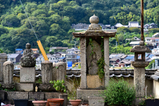 Historic stone jizo statue and lanterns standing in front of a scenic port town in Tomonoura, Hiroshima, Japan