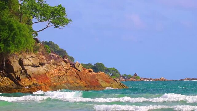 Sun turquoise clear water strong waves rocks Merlin Beach Thailand.