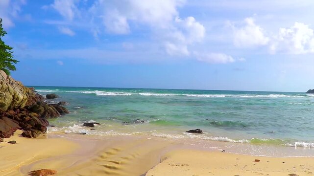 Sun turquoise clear water strong waves rocks Merlin Beach Thailand.