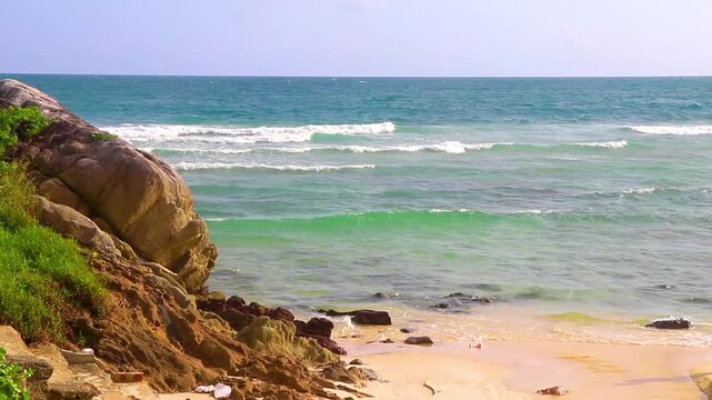 Sun turquoise clear water strong waves rocks Merlin Beach Thailand.