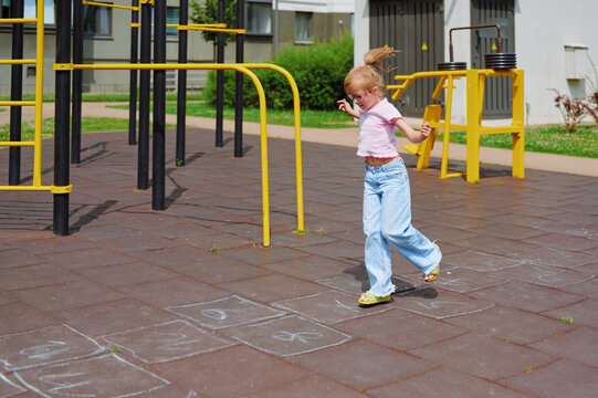 Energetic girl having fun playing hopscotch at the local park playground