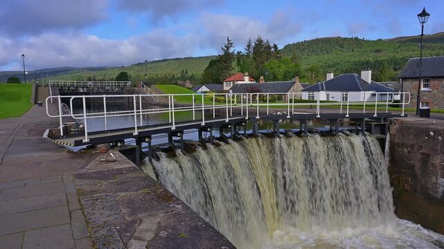 Eine Schleuse mit rauschendem Wasser, umgeben von B&auml;umen und einer H&uuml;gellandschaft, Kaledonischer Kanal, Fort Augustus, Loch Ness, Schottland, Vereinigtes K&ouml;nigreich, Gro&szlig;britannien
