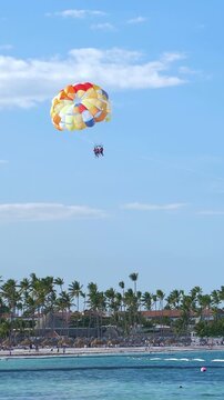 People having fun doing parasailing above Caribbean Sea. Vertical footage