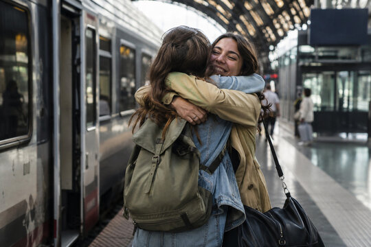 Emotional real photo style reunion at a train station, capturing joy, relief, and affection as loved ones reconnect after time apart in a travel setting.