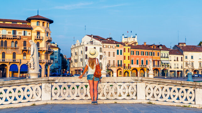back view of woman traveler with backpack standing on bridge in prato della valle square padua, tour tourism in italy