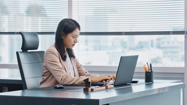 Young Asian Businesswoman Working on Laptop Computer at Office Desk, Modern Workplace Concept