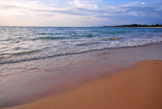 The sandy beach and the waves at sunset at Nai Thon Beach, Phuket.