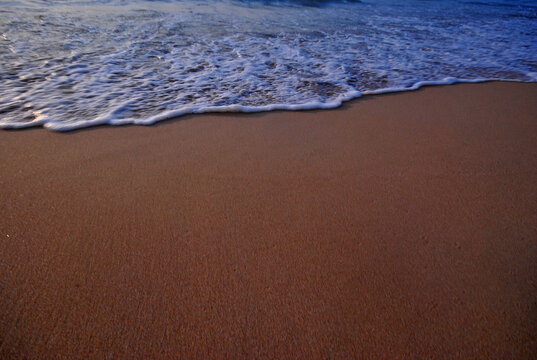 The sandy beach and the waves at sunset at Nai Thon Beach, Phuket.