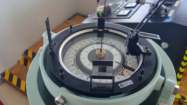 Close-up of a marine magnetic compass with an azimuth ring and sighting vane, used for navigation, bearing measurements, and directional orientation aboard a vessel
