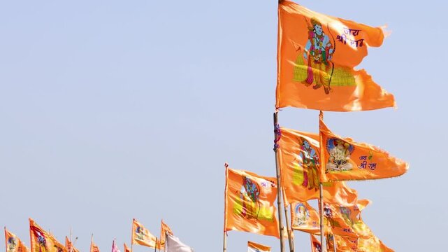 saffron religious flags featuring Lord Rama imagery fluttering against clear blue sky