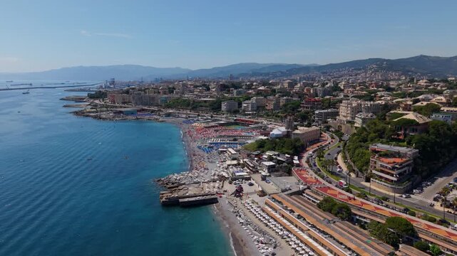 Aerial drone shot of Corso Italia coastline, busy beach, and cityscape in Genova, Italy