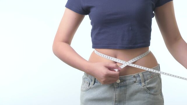 Confident proud woman uses white tape to measure slim waist during successful healthy weight loss journey promoting fitness diet body progress