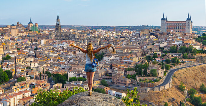 Happy woman with open arms enjoying Toledo cityscape in Spain, freedom and travel concept