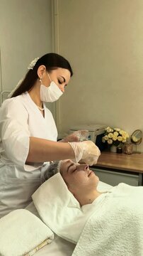 Esthetician Cleansing Teenage Girl Face During Facial Treatment
