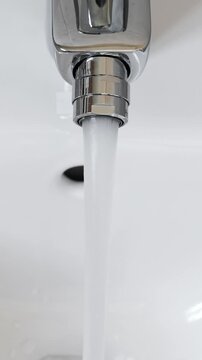 White ceramic bidet at modern restroom. Water is running. Nobody. Vertical footage