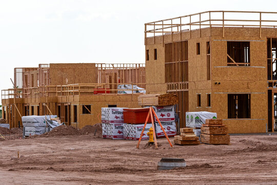 Multistory apartment buildings under construction with wood framing and building materials, illustrating multifamily housing development, residential construction, and real estate growth