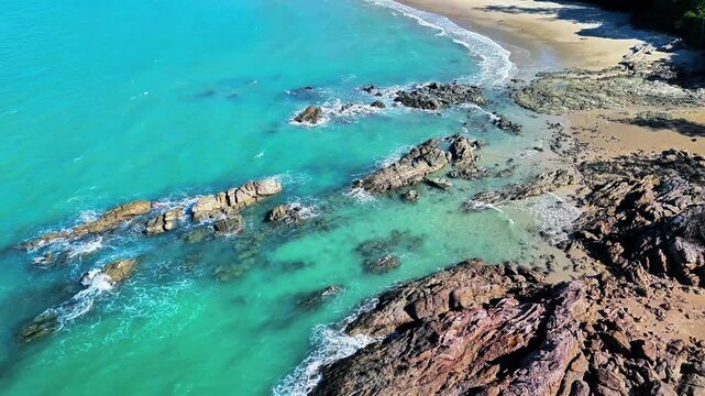 Aerial drone view of a hidden tropical beach with turquoise lagoon, granite reefs, crystal clear water and untouched sandy shoreline in paradise