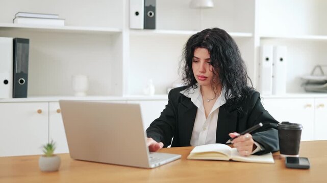 Business woman focused on work at laptop, taking important notes. Shows concentration and dedication in modern office setting. Engaged in task, feeling diligent and productive.