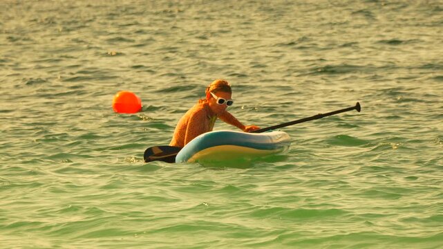 Woman paddling ocean inflatable board smiling happy tourist enjoying warm turquoise sea water vacation.